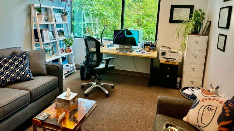 Dr. Novak’s professional counseling office in Oregon, showing a serene interior with natural light and views of a lush forest.